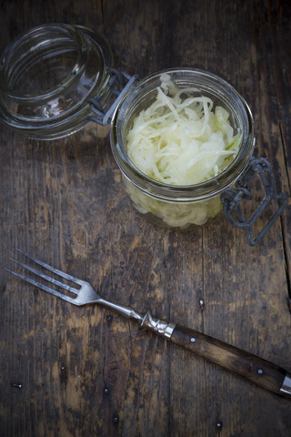 Preserving jar of cabbage salad and fork on wooden table stock photo