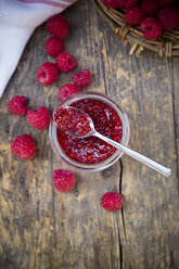 Glass of raspberry jam and raspberries on wooden table, elevated view - LVF001069