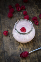 Glass of raspberry yogurt and raspberries on wooden table, elevated view - LVF001066