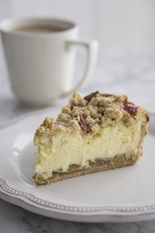 Stück Rhabarber-Käsekuchen auf Teller mit Tasse Kaffee, lizenzfreies Stockfoto