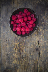Bowl of raspberries on wooden table, view from above - LVF001063