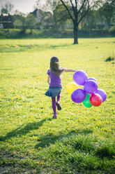 Kleines Mädchen mit Luftballons läuft auf einer Wiese - SARF000491