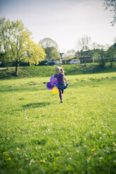 Little girl with balloons running on a meadow - SARF000486