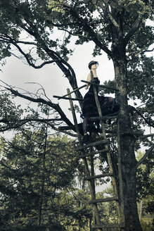 Deutschland, Frau mit verbundenen Augen auf Hochsitz in Baum - FC000041