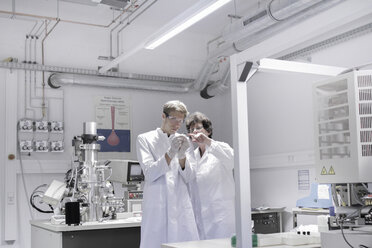 Zwei Wissenschaftler stehen in einem analytischen Labor mit einem Rasterelektronenmikroskop - SGF000586