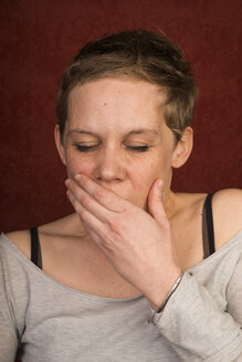 Gähnende Frau, die ihren Mund mit der Hand bedeckt - FBF000357