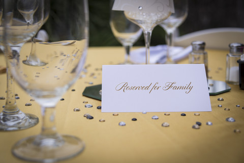 Table setting with wine glasses, salt and pepper shakers and a paper sign showing reserved for family stock photo