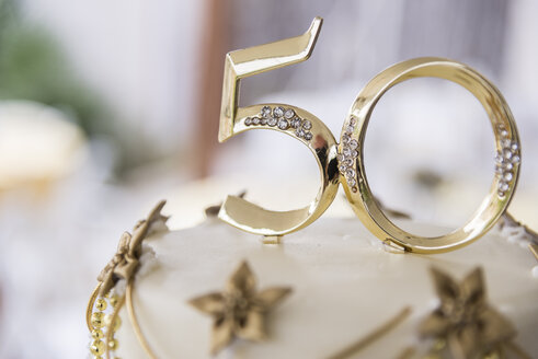 Number 50 in golden plastic attached to the top of a wedding anniversary cake - ABAF001314