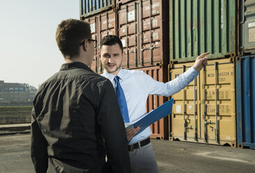 Geschäftsmann im Gespräch mit Teenager am Containerterminal - UUF000320