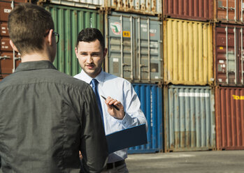 Geschäftsmann im Gespräch mit Teenager am Containerterminal - UUF000321
