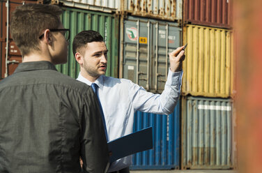 Geschäftsmann im Gespräch mit Teenager am Containerterminal - UUF000322