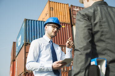 Geschäftsmann im Gespräch mit Teenager am Containerterminal - UUF000324