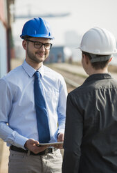 Businessman talking to teenager at container terminal - UUF000327