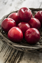 Bowl of red plums on wooden table - SARF000515