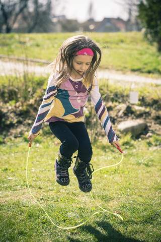 Kleines Mädchen springt Seil im Garten, lizenzfreies Stockfoto