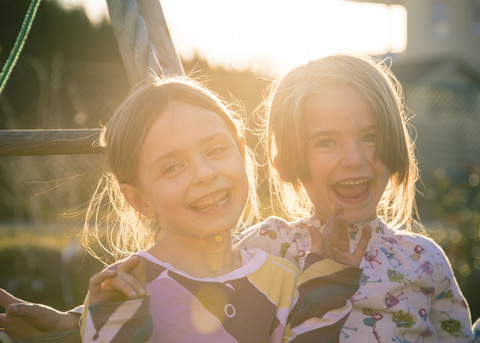 Porträt von zwei lachenden kleinen Mädchen bei Gegenlicht, lizenzfreies Stockfoto