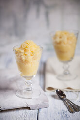 Two glasses of orange granita and tea spoons on cloth and wooden board - SBDF000793