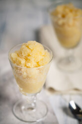 Two glasses of orange granita and tea spoons on cloth and wooden board - SBDF000794