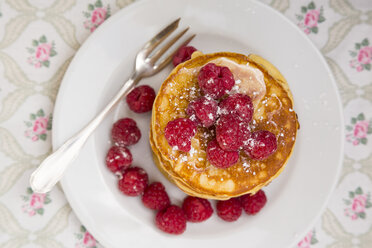 Pancakes with honey, raspberries and icing sugar on plate, view from above - LVF001099