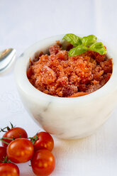 Marble bowl of tomato granita garnished with basil leaves and cherry tomatoes on white cloth - LVF001106