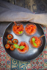 Bowl with glasses of tomato granita garnished with basil leaves and cherry tomatoes, view from above - LVF001108