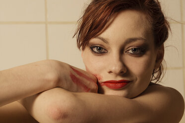 Portrait of young woman with lipstick on cheek in bath tub - FBF000375