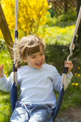Porträt eines glücklichen kleinen Mädchens, das im Garten schaukelt - LVF001110