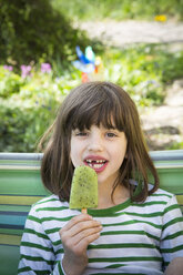 Porträt eines Mädchens mit Zahnlücke, das einen Kiwi-Eislutscher hält - LVF001111