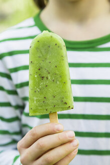 Girl holding kiwi ice lolly, close-up - LVF001113