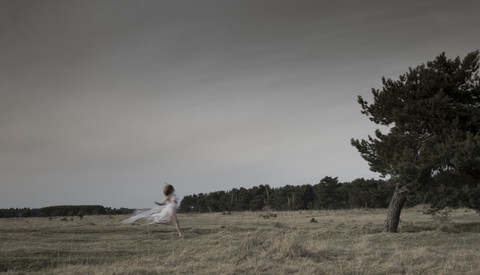 Deutschland, Bayern, Fröttmaninger Heide, junge Frau im Tüllkleid und beim Laufen, lizenzfreies Stockfoto