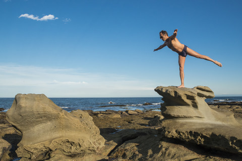 Australien, New South Wales, Teegärten, Mann auf Felsen in Yogastellung, lizenzfreies Stockfoto
