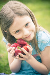 Portrait of smiling little girl holding handful of strawberries - SARF000519