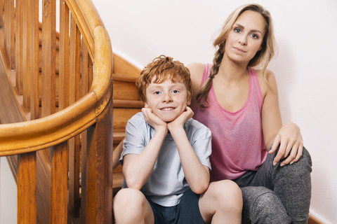 Porträt von Mutter und Sohn auf der Treppe ihres Hauses sitzend, lizenzfreies Stockfoto