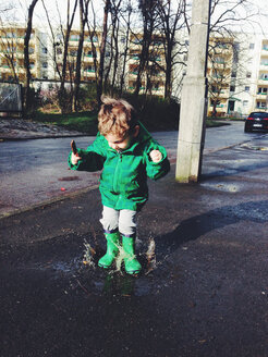 Germany, Saar mouth, Little boy jumping in the puddle - AFF000059