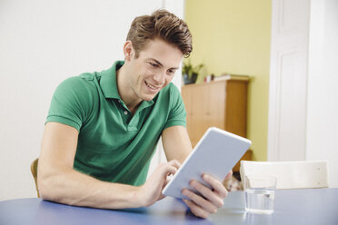 Portrait of young man using tablet computer at home - MFF001038