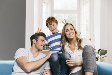 Portrait of young family sitting on their couch at living room - MFF001075