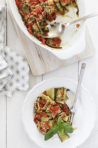 Zucchini-Tomaten-Gratin in Gratinform und auf Teller, lizenzfreies Stockfoto