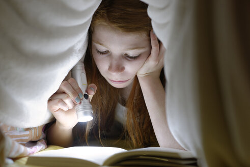 Porträt eines Mädchens, das heimlich im Bett unter der Decke ein Buch liest - LBF000694