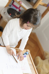 Girl at home writing on sheet of paper - LAF000780