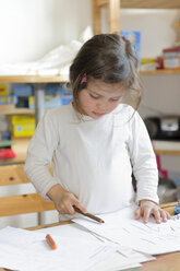 Girl at home writing on sheet of paper - LAF000781