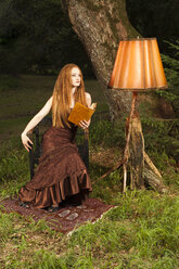 Young woman with evening dress sitting on chair in park by night - FCF000056