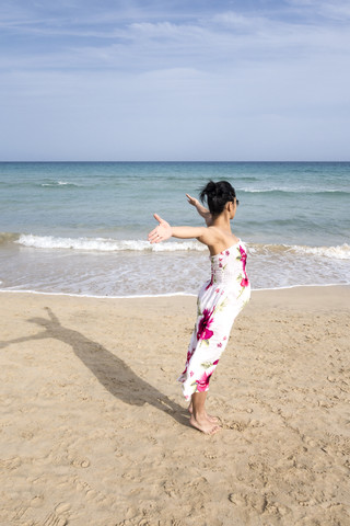 Spain, Fuerteventura, Pregnant woman with outstretched arms on beach stock photo