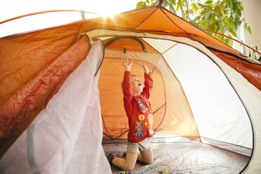 Kleiner Junge, der bis zum Dach eines orangefarbenen Zeltes reicht - MFF001088