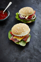 Zwei vorbereitete Burger, Senf und Ketchup auf dunklem Grund - KSWF001261