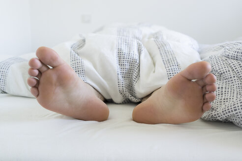 Füße einer jungen Frau, die aus dem Bett ragen - FLF000412