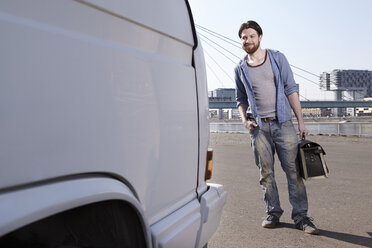 Mann mit Werkzeugtasche am Auto - FMKF001167