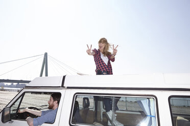 Excited woman gesticulating on minivan - FMKF001165
