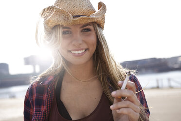 Porträt einer lächelnden jungen Frau mit Cowboyhut - FMKF001174
