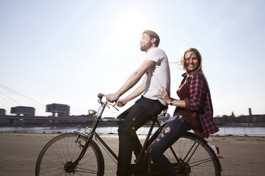 Glückliches Paar beim Fahrradfahren am Flussufer - FMKF001175