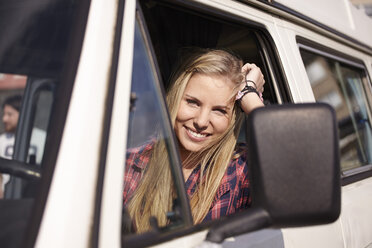 Smiling young woman in minivan - FMKF001233